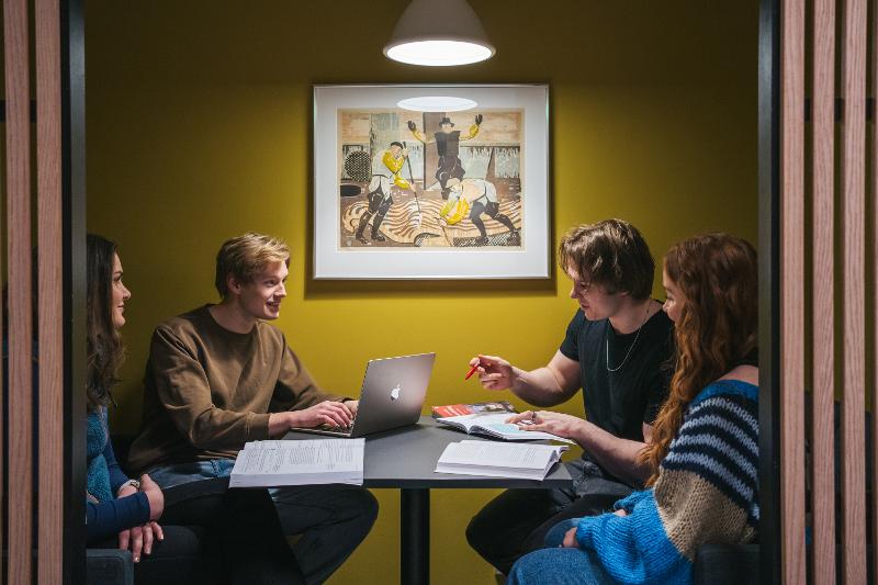 Fire unge menensker diskuterer rundt et bord